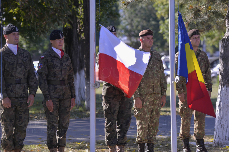 Soldați români și polonezi, aliniați sub steagurile naționale, într-o ceremonie militară ce simbolizează cooperarea și parteneriatul de securitate dintre România și Polonia