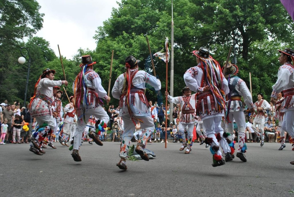 Dansul Căluților în ajun de Anul Nou, cu tineri purtând măști colorate și costume tradiționale românești