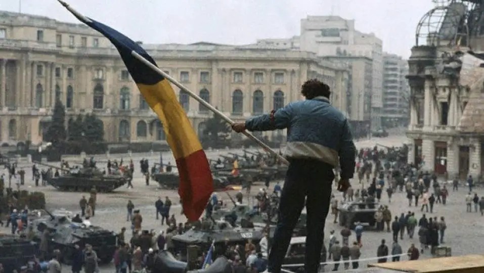 Protestatari în Bucuresti fluturând steaguri cu stema decupată în timpul Revoluției Române din 1989